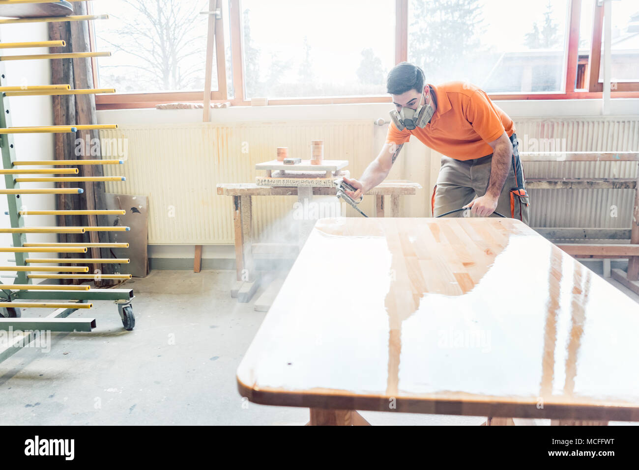 Carpenter uomo la spruzzatura di vernice su un tavolo che lavora su Foto Stock