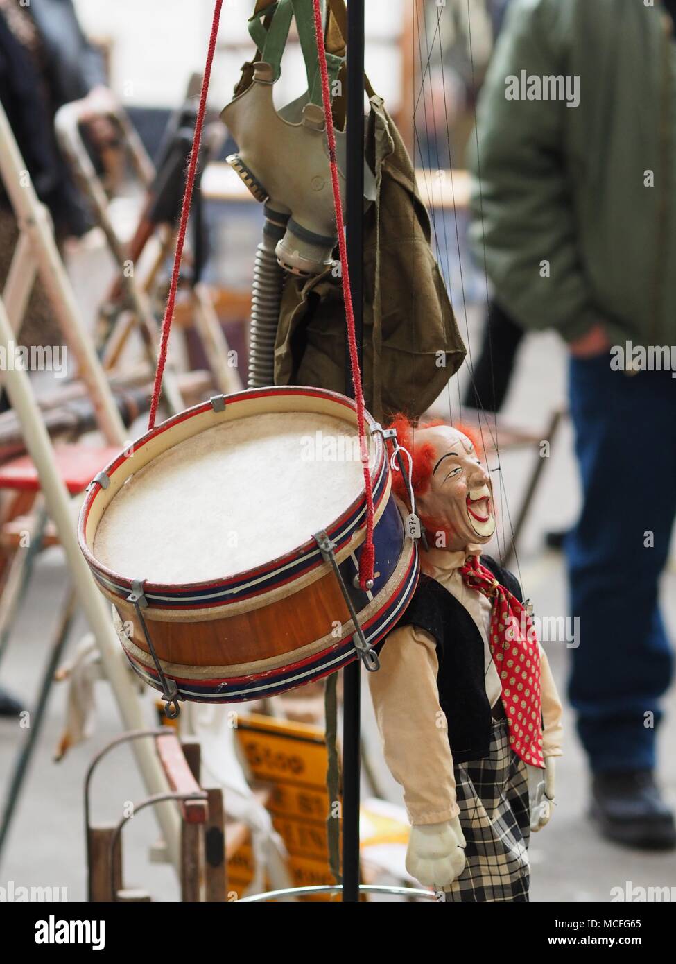 Drum clown puppet e maschera a gas appeso su un cappotto uno stand alla fiera antiquaria Foto Stock