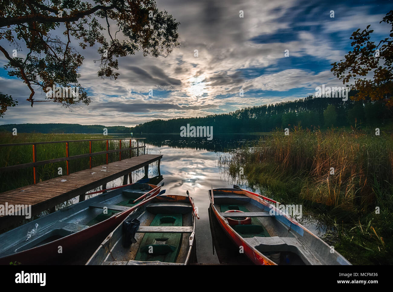 Dock in barca sul lago, albero riflessioni in acqua calma Foto Stock