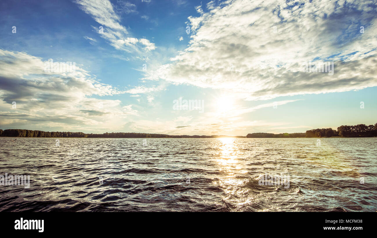 Lago ondulato durante la giornata estiva; sole dietro le nuvole Foto Stock