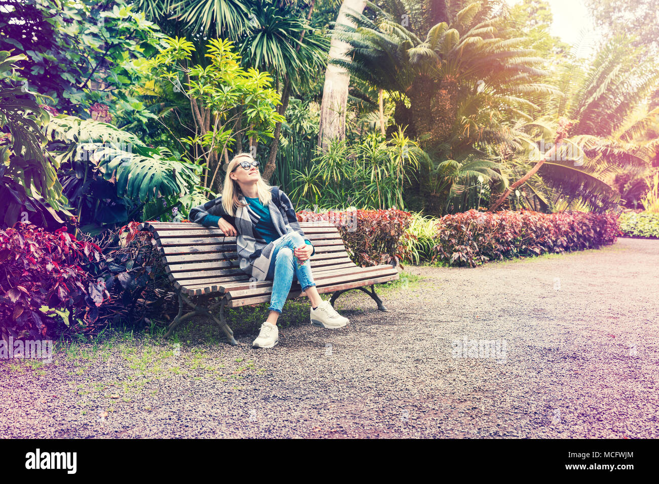 Donna seduta e rilassante sul banco a Botanical Garden park Foto Stock