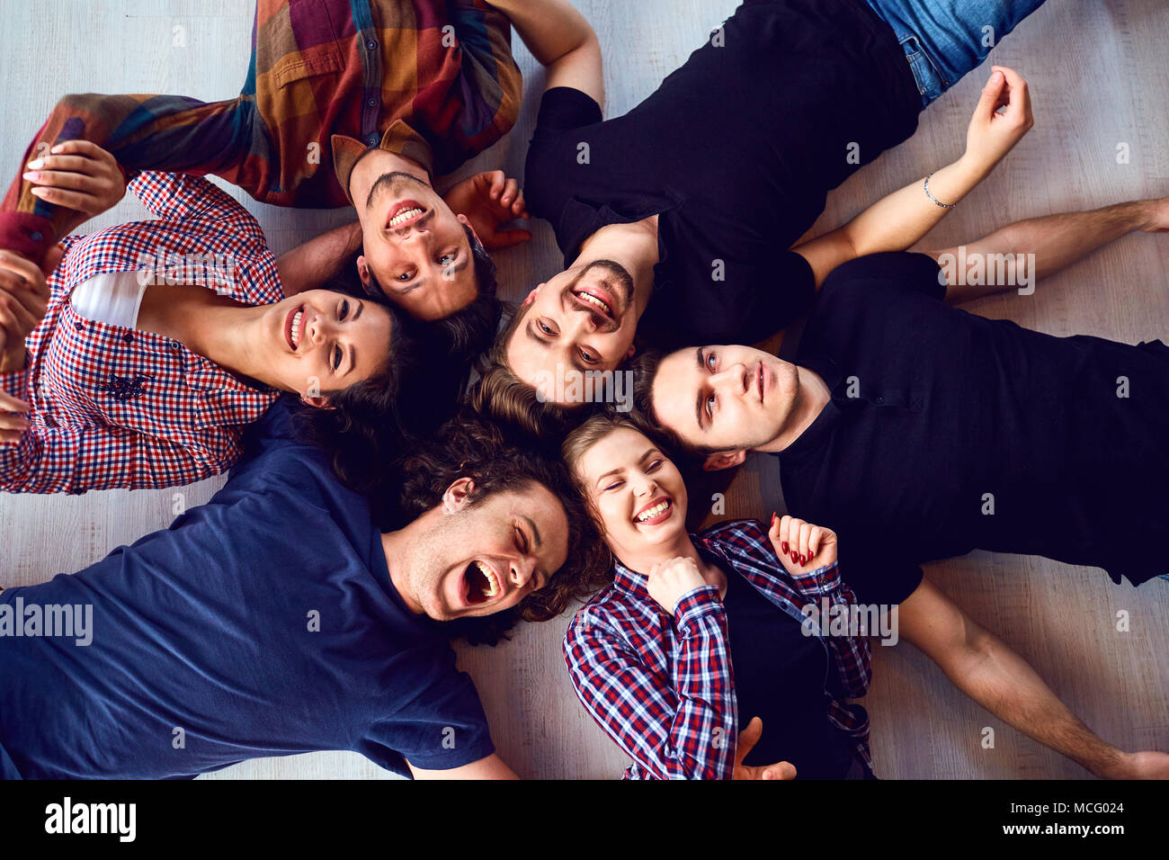 Vista dall'alto. Un gruppo di amici stanno ridendo sdraiato sul pavimento in camera. Foto Stock