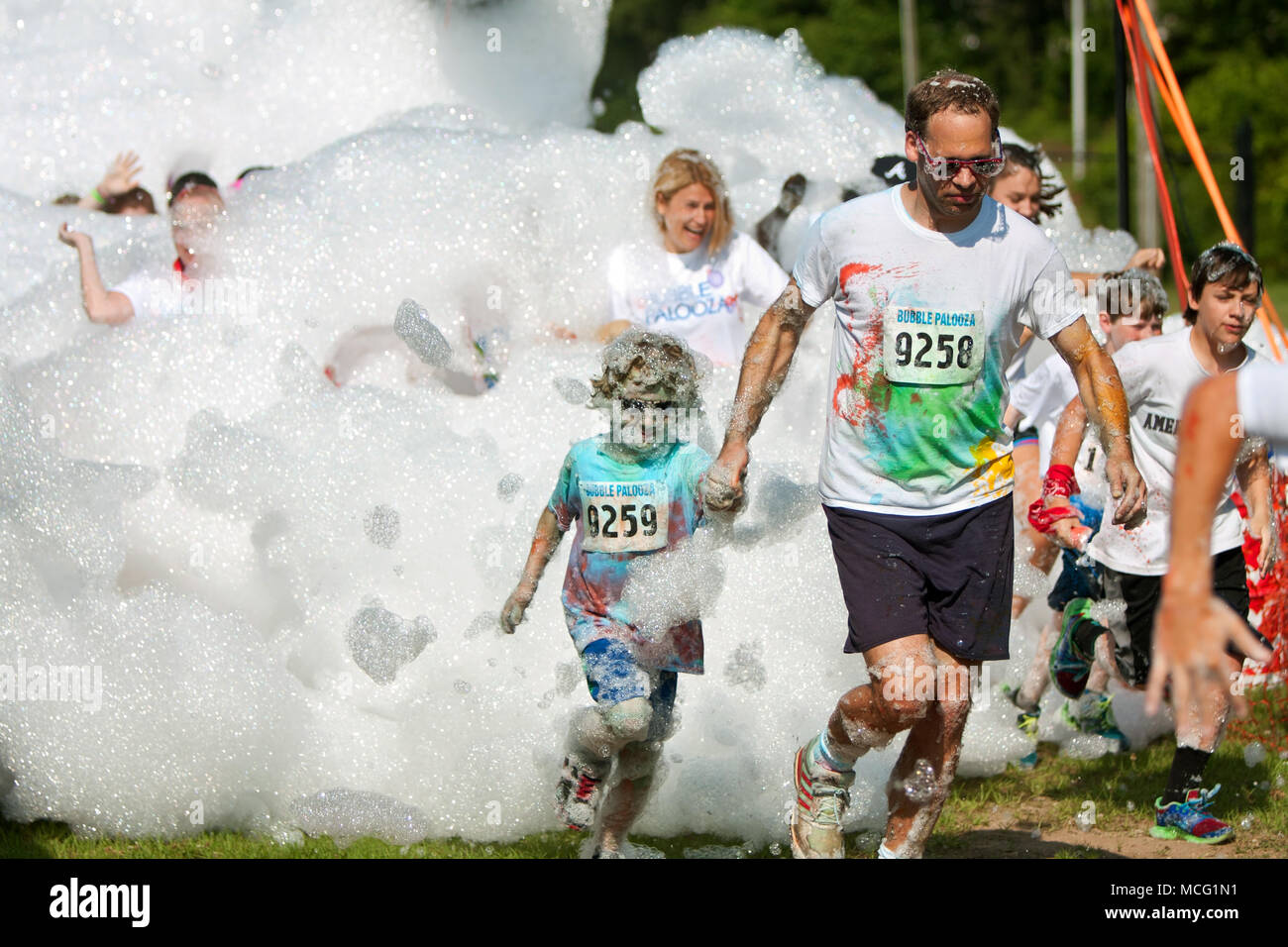 Lawrenceville, GA, Stati Uniti d'America - 31 Maggio 2014: un padre e figlio eseguito attraverso un enorme nube di bolle e di schiuma a bolla Palooza. Foto Stock