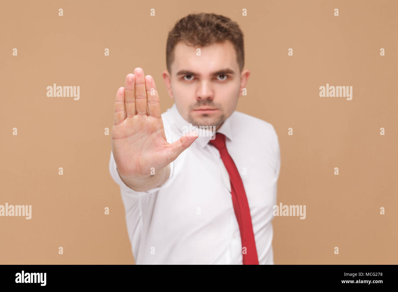 L'uomo arrabbiato che mostra la telecamera a mano di arresto, nessun segno. La gente di affari concetto buone e cattive emozioni e sentimenti. Studio shot, isolato sulla luce marrone backg Foto Stock