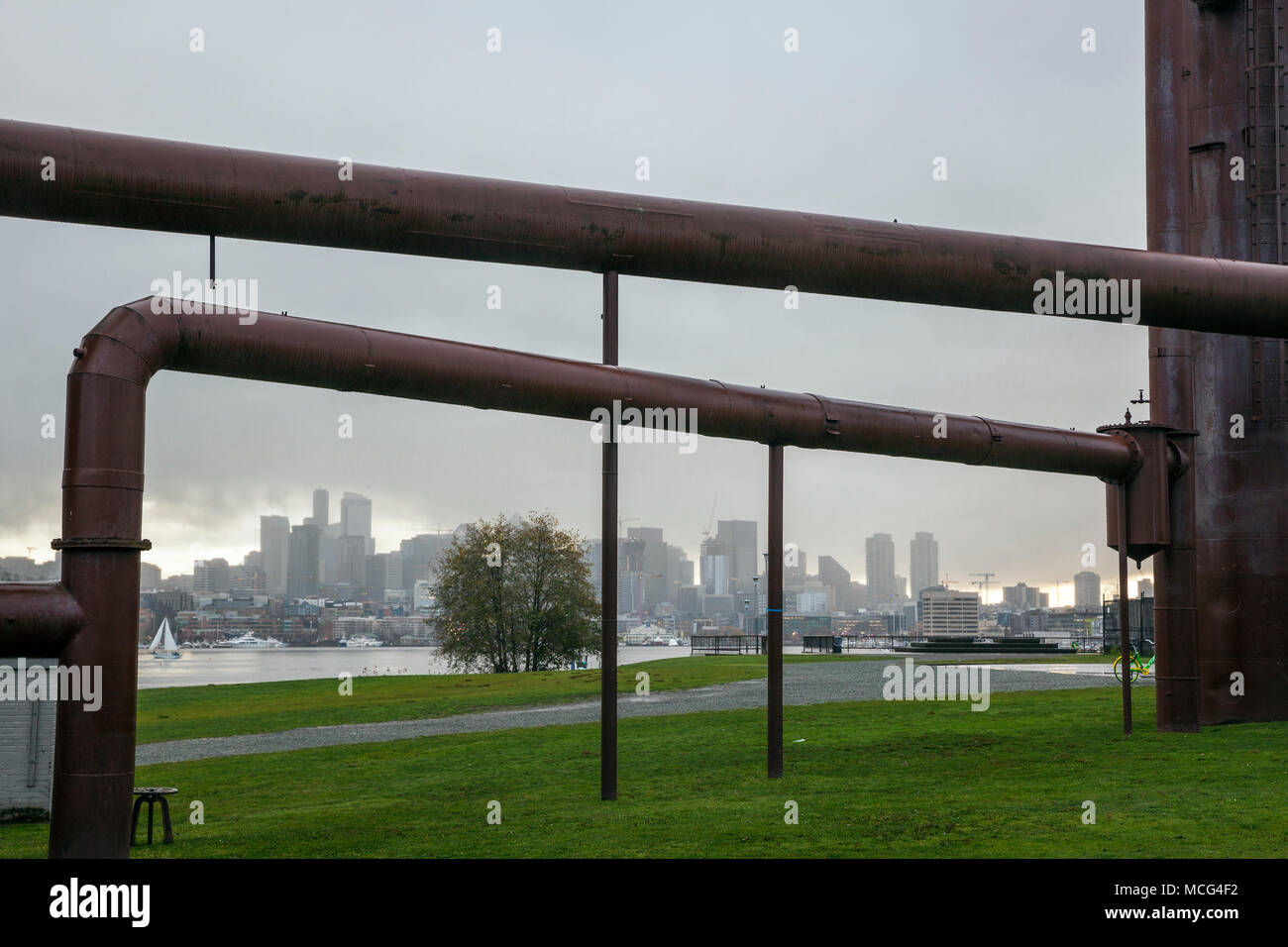 WA14367-00...WASHINGTON - Seattle skyline della città incorniciata dai tubi industriali a gas Parco di opere in un giorno di pioggia. Foto Stock