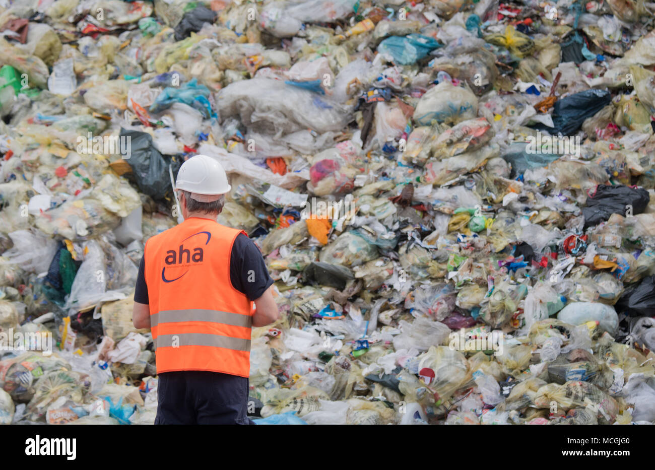 16 aprile 2018, Germania, Hannover: un dipendente a piedi nella parte anteriore di imballaggi leggeri e riciclaggio giallo sacchetti giaceva su una discarica di 'aha da Zweckverband Abfallwirtschaft Regione Hannover" (lit. gestione dei rifiuti azienda Hannover). In modo non corretto dei rifiuti separati è spesso smaltiti nei bidoni gialli. Il contingente di smaltimento non corretto è compreso tra 40 e 60%, secondo l'Associazione tedesca per la Materie prime secondarie e la gestione dei rifiuti. Foto: Julian Stratenschulte/dpa Foto Stock