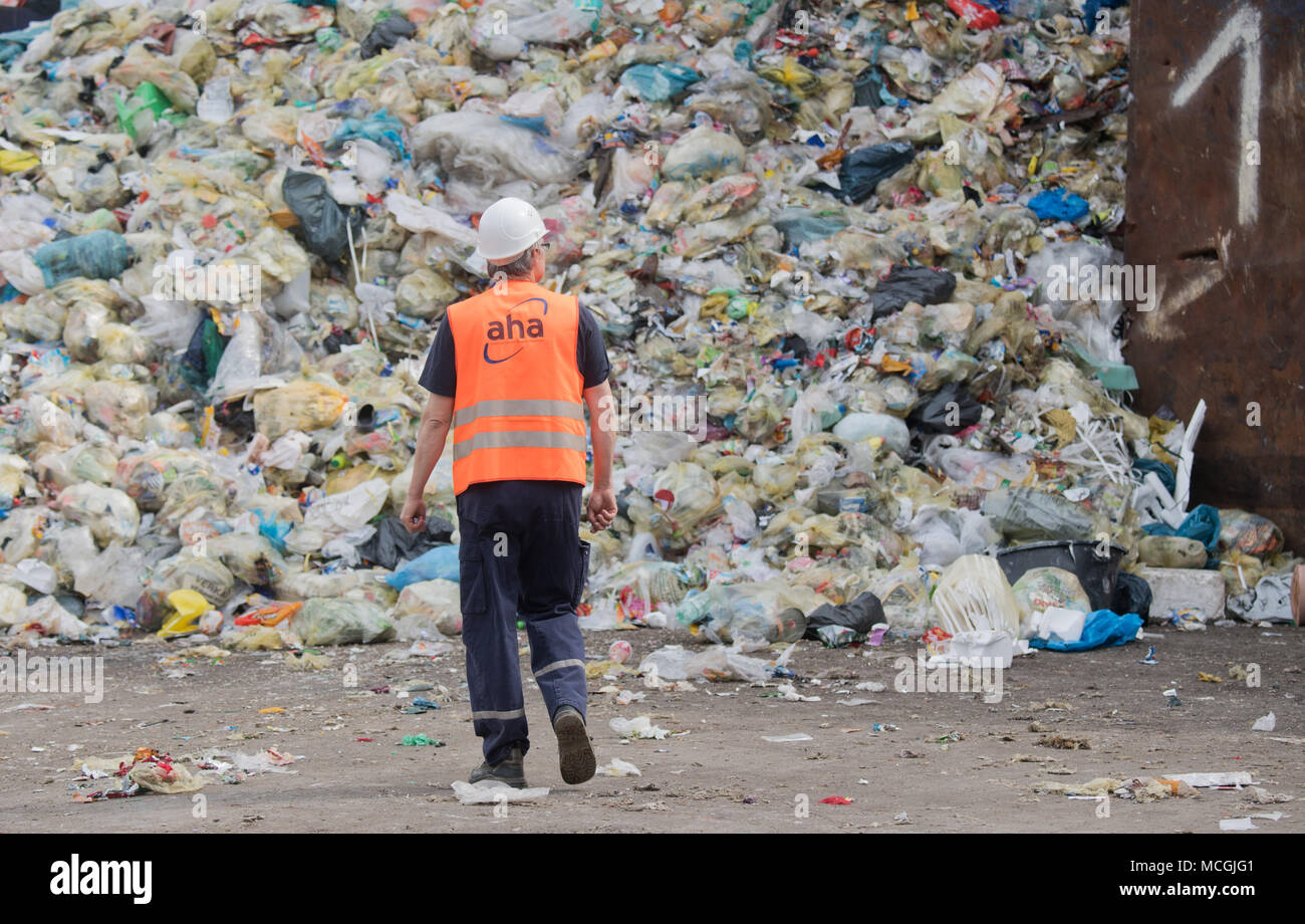 16 aprile 2018, Germania, Hannover: un dipendente a piedi nella parte anteriore di imballaggi leggeri e riciclaggio giallo sacchetti giaceva su una discarica di 'aha da Zweckverband Abfallwirtschaft Regione Hannover" (lit. gestione dei rifiuti azienda Hannover). In modo non corretto dei rifiuti separati è spesso smaltiti nei bidoni gialli. Il contingente di smaltimento non corretto è compreso tra 40 e 60%, secondo l'Associazione tedesca per la Materie prime secondarie e la gestione dei rifiuti. Foto: Julian Stratenschulte/dpa Foto Stock