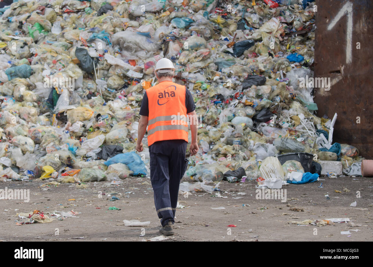16 aprile 2018, Germania, Hannover: un dipendente a piedi nella parte anteriore di imballaggi leggeri e riciclaggio giallo sacchetti giaceva su una discarica di 'aha da Zweckverband Abfallwirtschaft Regione Hannover" (lit. gestione dei rifiuti azienda Hannover). In modo non corretto dei rifiuti separati è spesso smaltiti nei bidoni gialli. Il contingente di smaltimento non corretto è compreso tra 40 e 60%, secondo l'Associazione tedesca per la Materie prime secondarie e la gestione dei rifiuti. Foto: Julian Stratenschulte/dpa Foto Stock