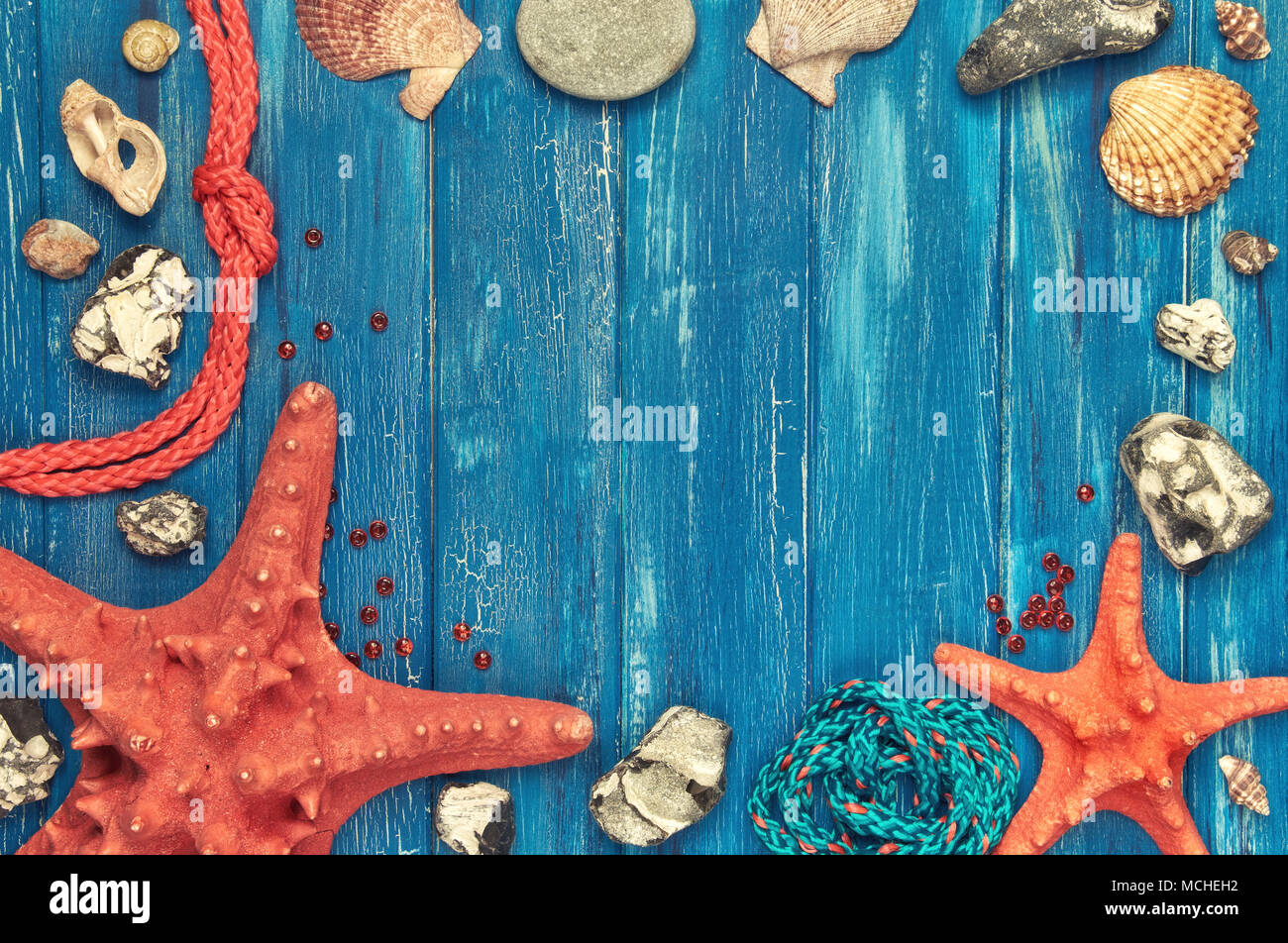 Lavagna con cornice fatta di conchiglie di mare, pietre, corda e pesce  stella blu su sfondo di legno Foto stock - Alamy