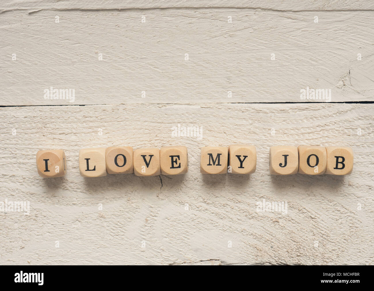 Dadi di legno con le parole io amo il mio lavoro su un bianco tavolo in legno Foto Stock