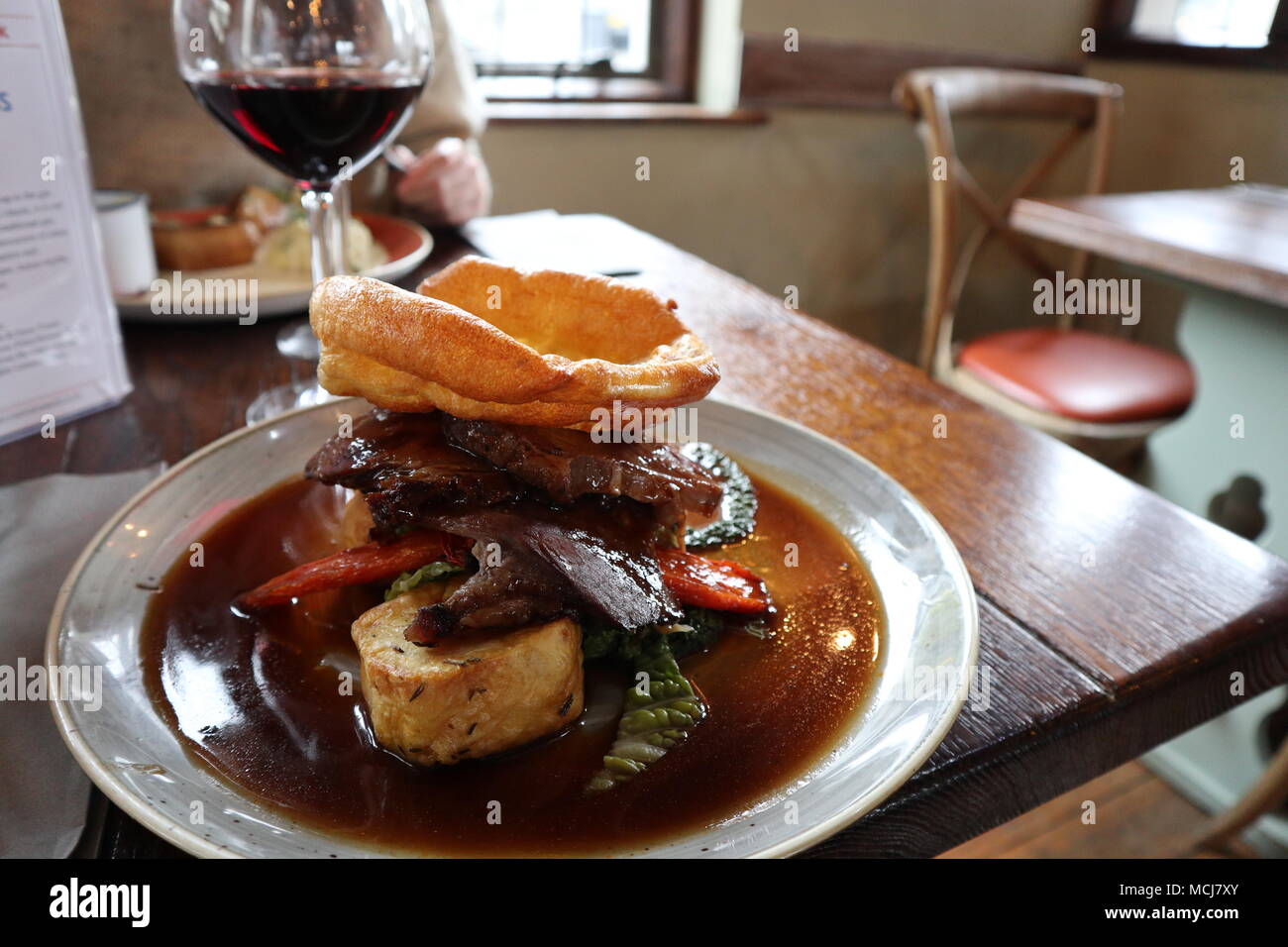 Un delizioso Arrosto domenicale in un classico pub inglese. Arrosto di manzo fesa con verdure di stagione, Yorkshire pudding e un bicchiere di Malbec vino rosso. Foto Stock
