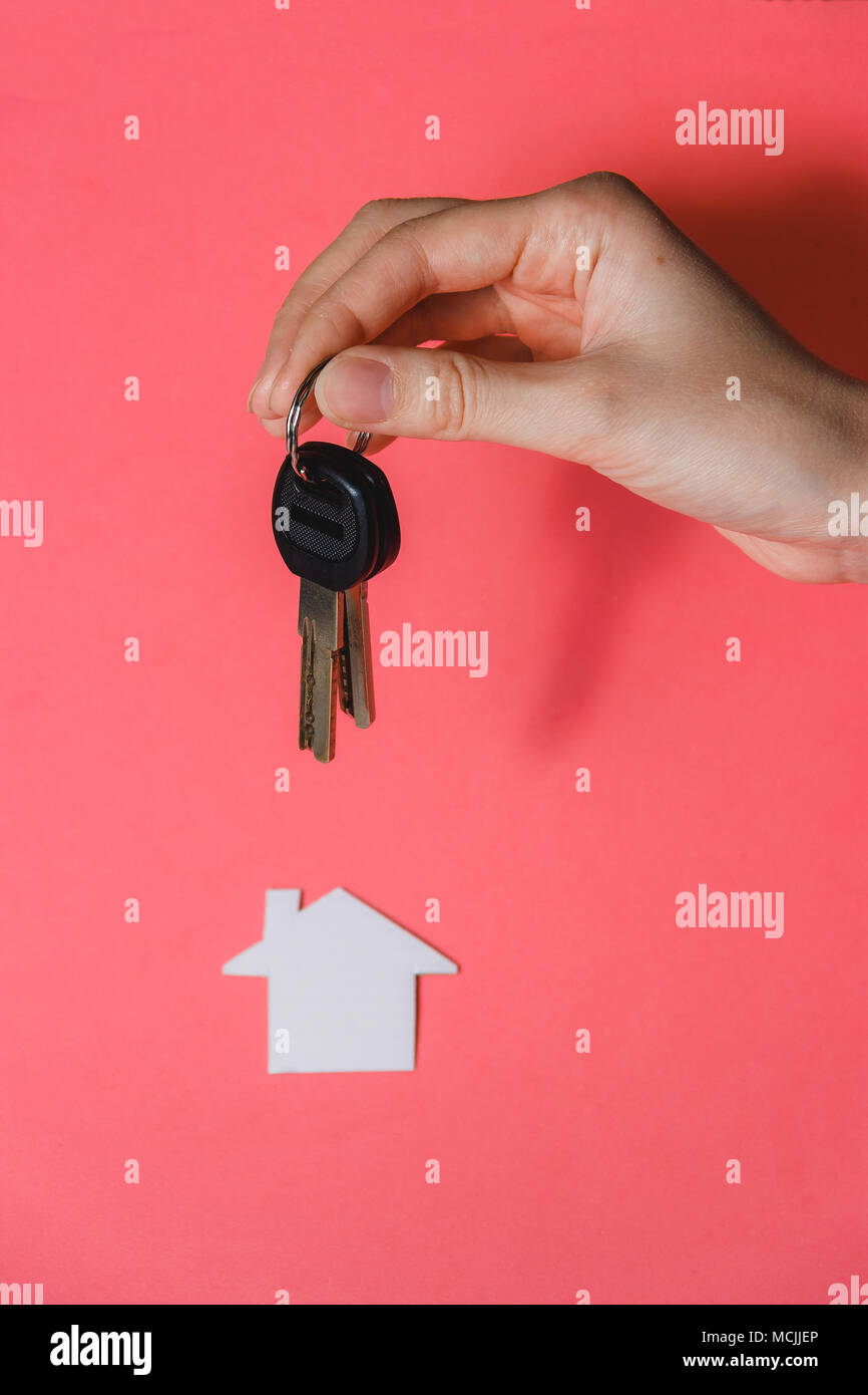 Mano umana in possesso della chiave di sogno avviato House contro sfondo rosa Foto Stock