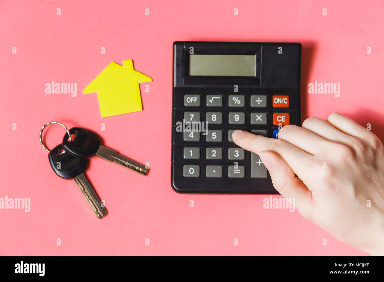 Close-up di donna mano utilizzando la calcolatrice con carta modello di casa sulla scrivania con schema Foto Stock