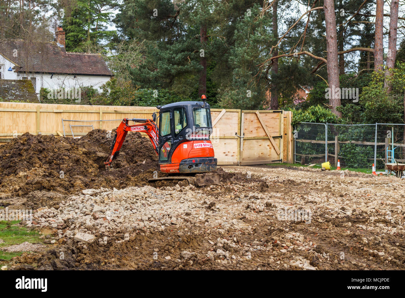 Orange Hitachi impianto pesante escavatore meccanico su un sito di costruzione di costruire una nuova casa su un materiale di riempimento o infill trama nel Surrey, Inghilterra sudorientale, REGNO UNITO Foto Stock