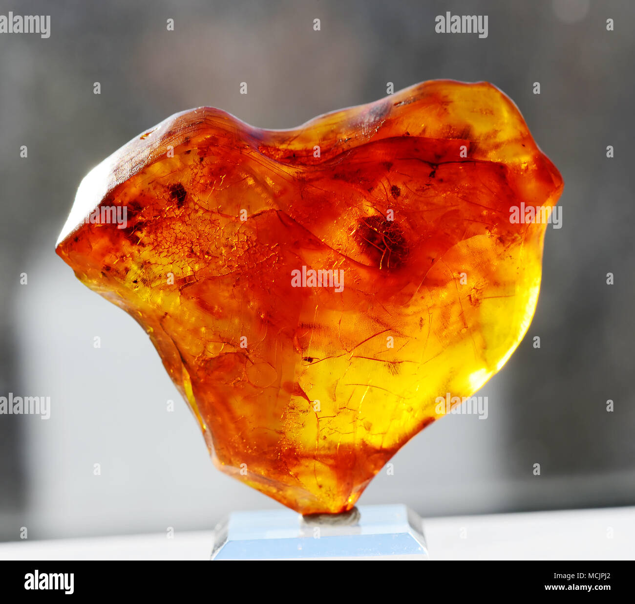 Bella orange translucent ambra baltica in forma di cuore su uno sfondo scuro Foto Stock