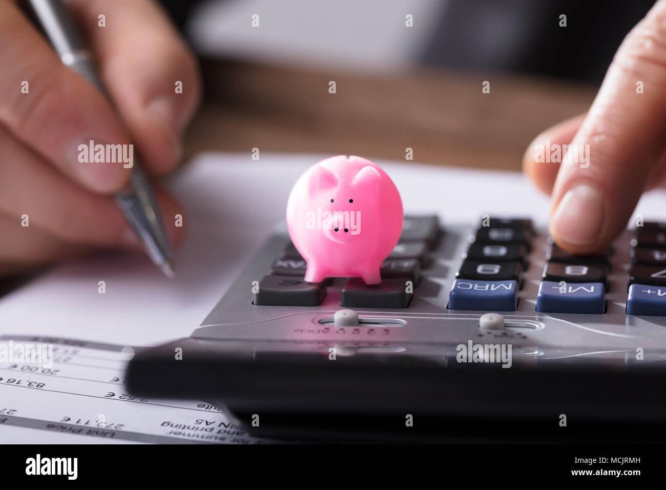 Close-up di un rosa Piggybank sulla calcolatrice di commercianti lavora su documenti Foto Stock