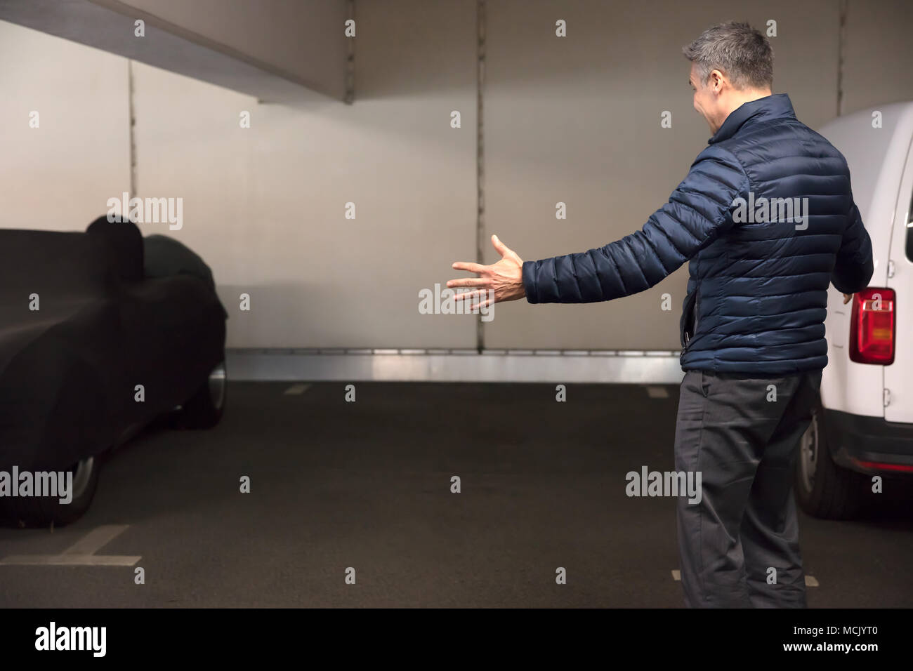 Vista posteriore di un scioccato uomo in piedi nel parcheggio dopo la sua auto è stata rubata Foto Stock