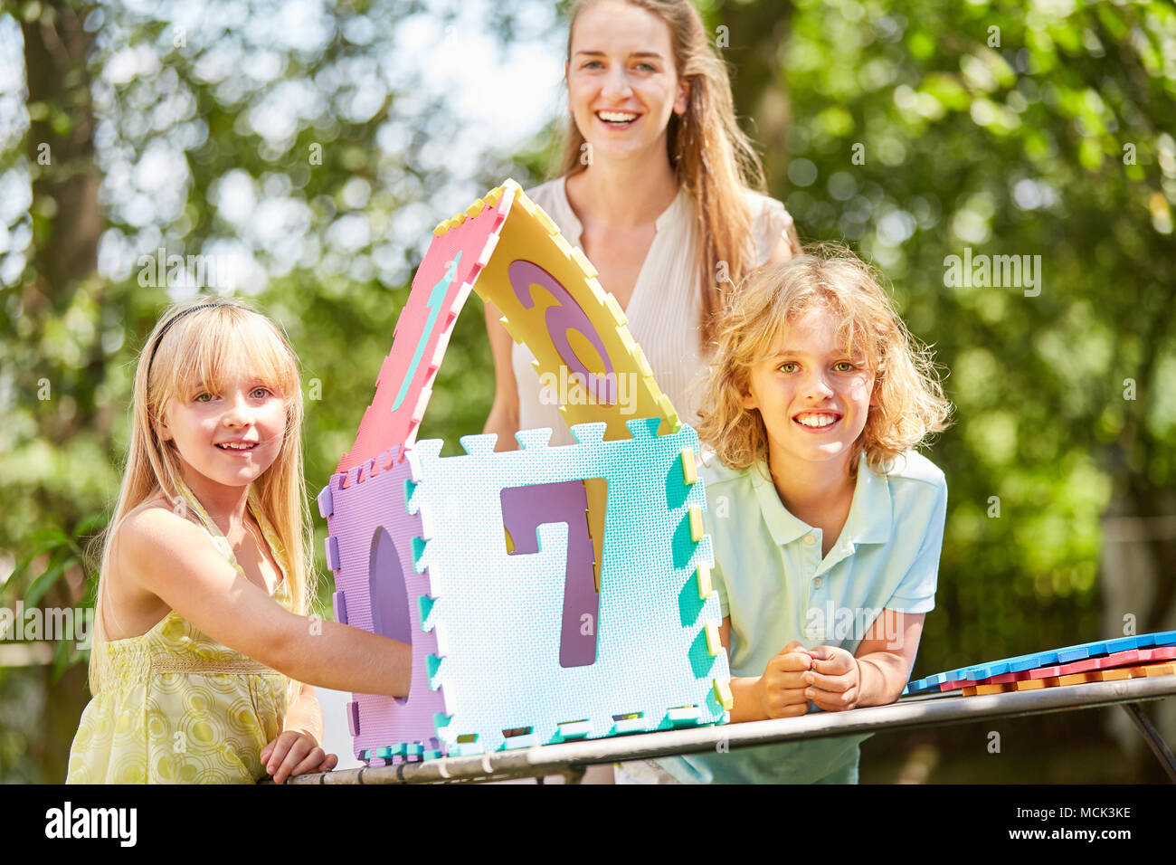 Madre e bambini costruire una casa puzzle come simbolo della loro casa da sogno Foto Stock
