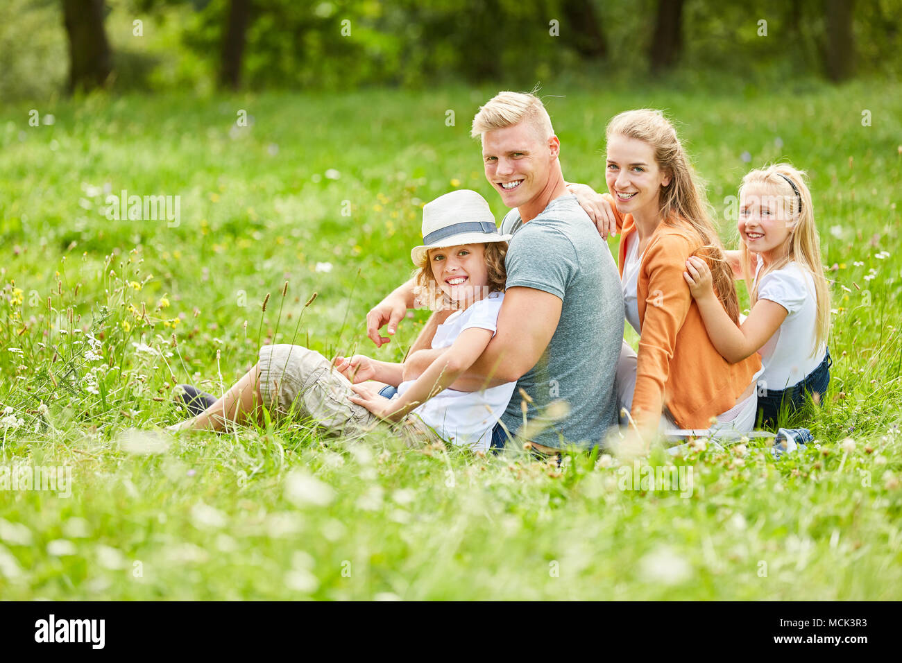 Famiglia con due bambini sono seduti tranquillamente su un prato in estate Foto Stock