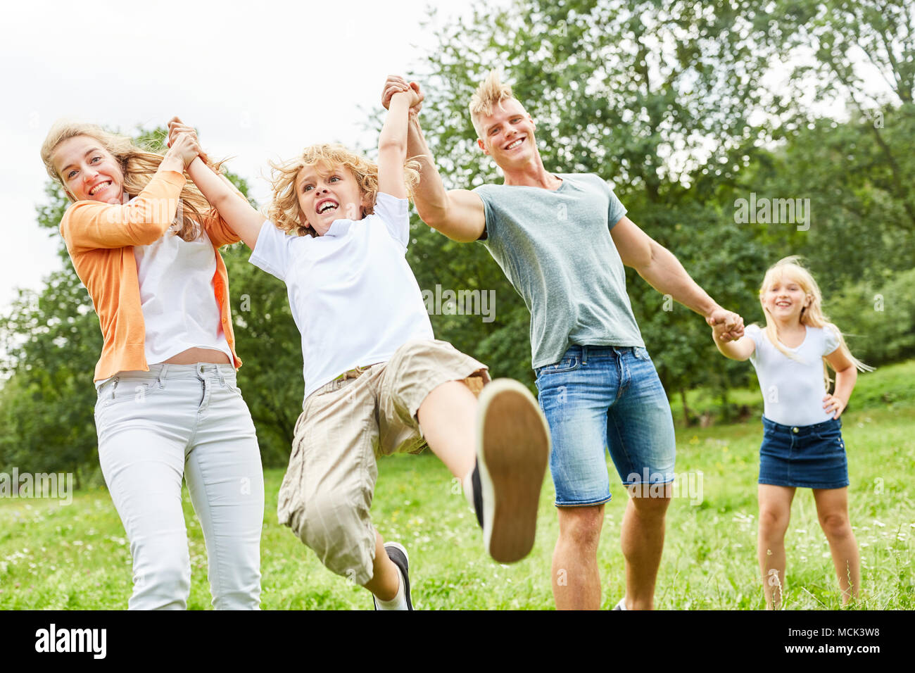 Ragazzo gioca comicamente con i suoi genitori e la sorella in giardino Foto Stock
