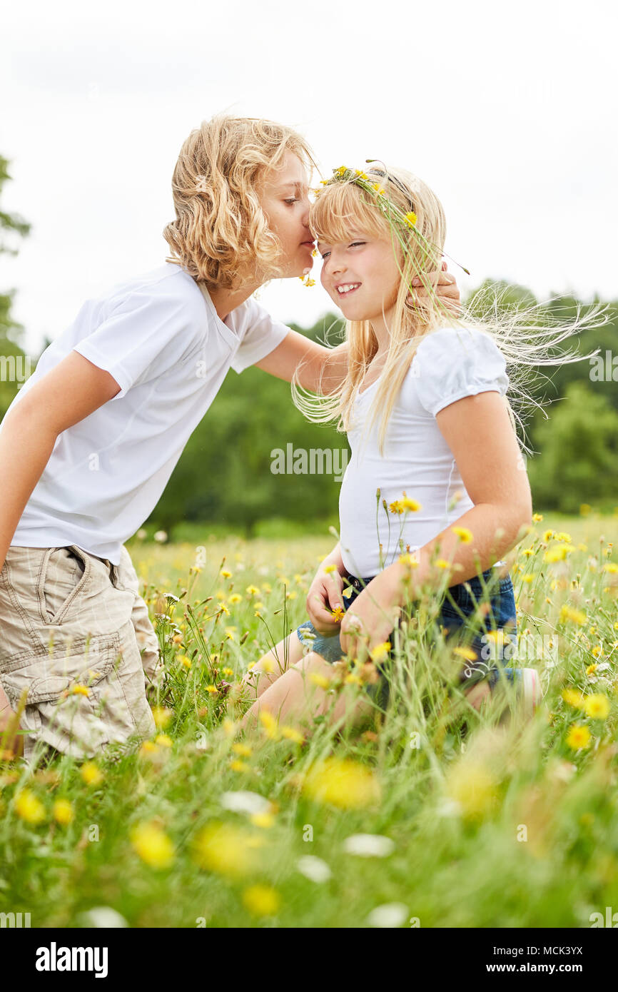Fratello amorevolmente bacia la sorella sulla fronte in un prato estivo Foto Stock