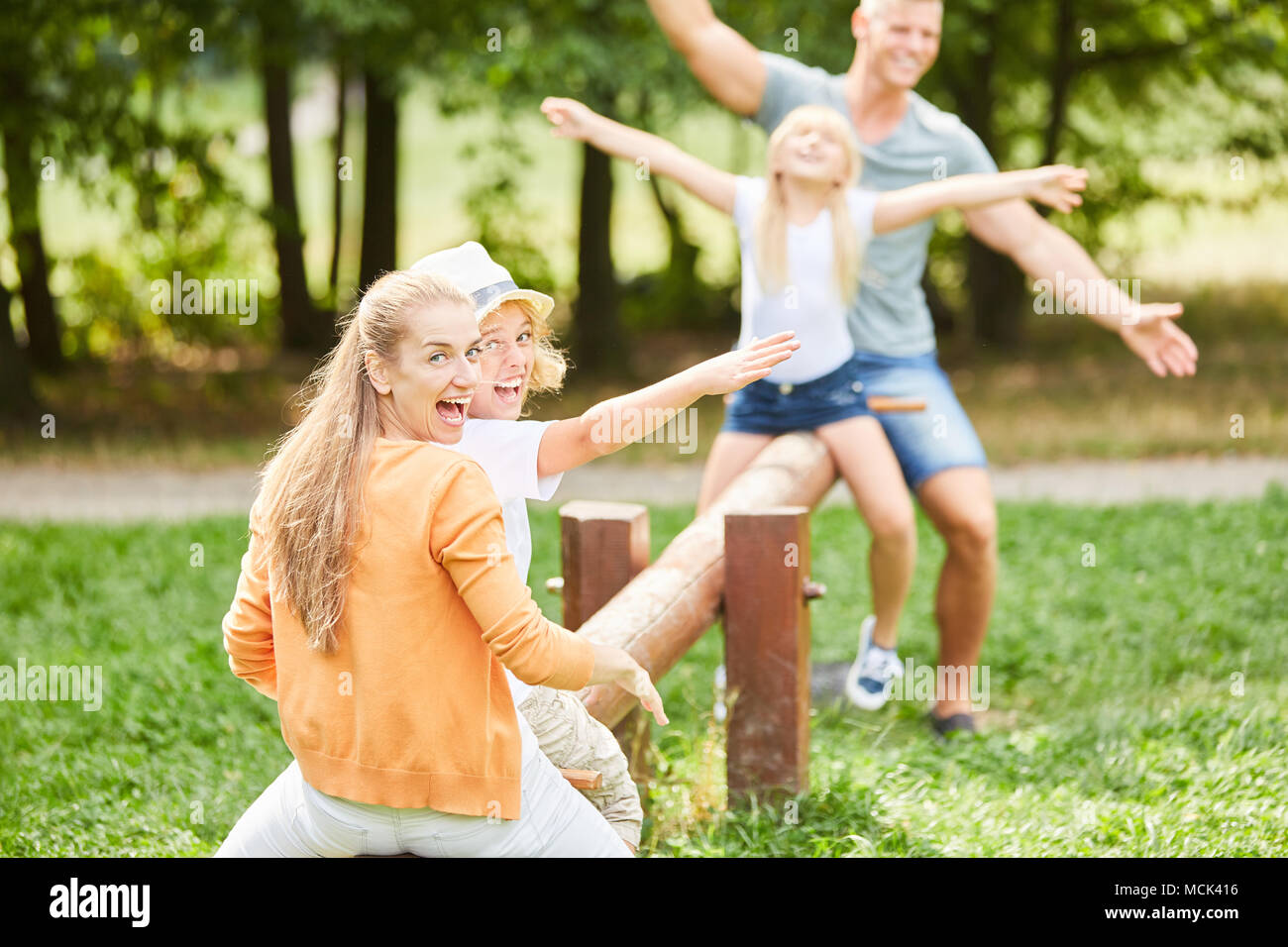 Famiglia attiva sul parco giochi ha un sacco di divertimento insieme sull'altalena Foto Stock