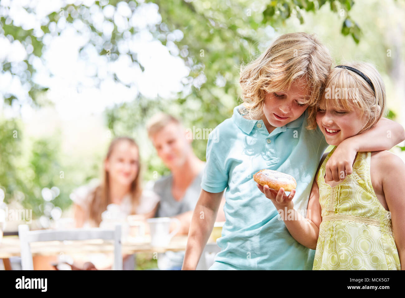 I gemelli giovane nibbles insieme un delizioso pezzo di torta in giardino Foto Stock