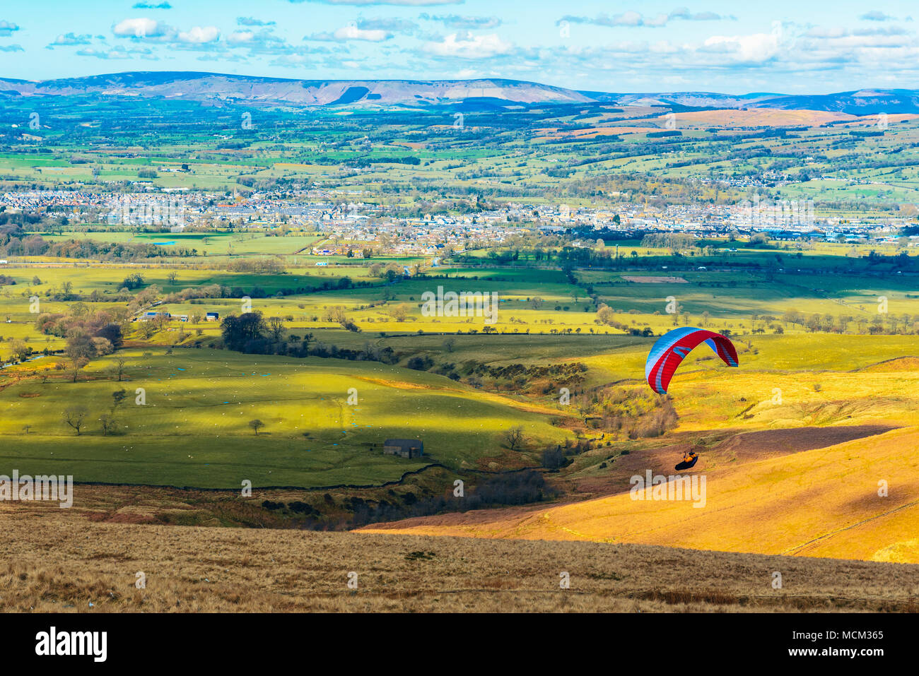 Parapendio al di sopra del Ribble Valley, Lancashire, Inghilterra visto dal sito di lancio su Pendle Hill con Clitheroe sotto e la Bowland Fells oltre Foto Stock