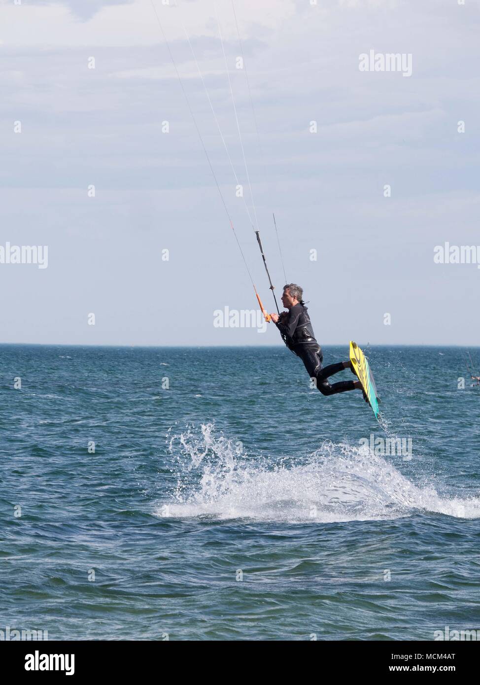 Kiteboarders e kitesurfisti sulla Port Phillip Bay Australia accelerando attraverso acqua, facendo trucchi, volare in aria su un caldo e soleggiato cielo blu giorno Foto Stock