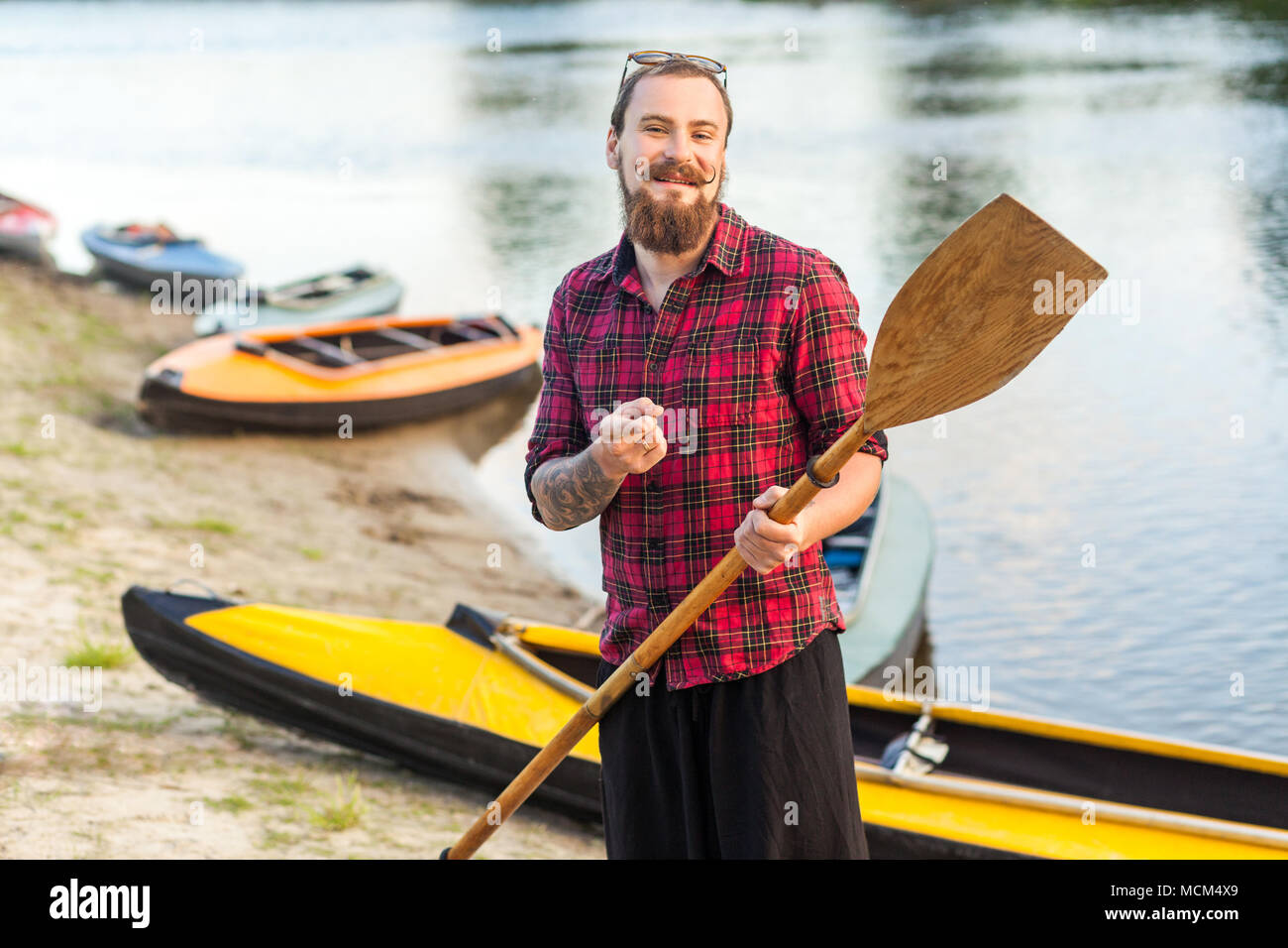 Uomo bello azienda pala e in piedi vicino al kayak sul fiume Foto Stock