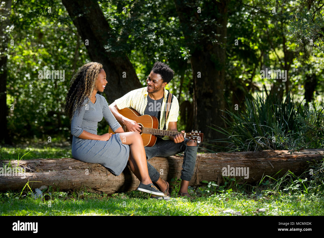 Uomo a suonare la chitarra per una donna in un parco Foto Stock