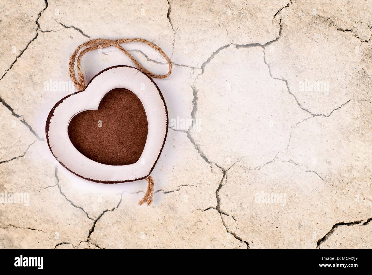 Cornice fotografica in legno in forma di cuore su asciutto incrinato sfondo di terra Foto Stock