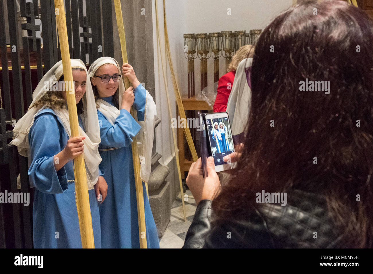 Tenerife, Isole Canarie, ragazze preparando a condurre la Domenica delle Palme Settimana Santa processione nella cattedrale di San Cristóbal de La Laguna di scattare foto sul loro smart phone Foto Stock