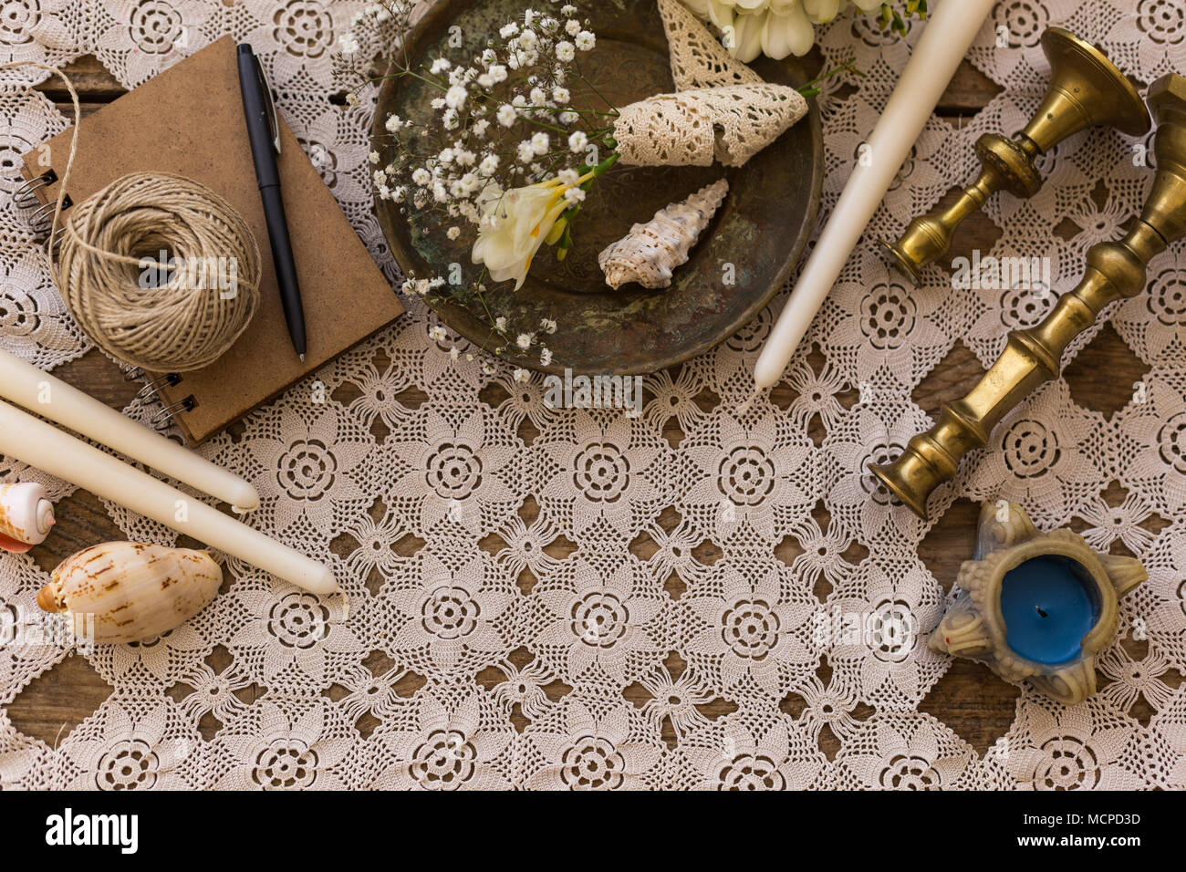 Rustico concetto di matrimonio. Vista Top Shot di notepad, piastra vintage, gypsophila fiori, vintage portacandele e candele sul Pizzo del piano portapaziente. Copia dello spazio. Foto Stock