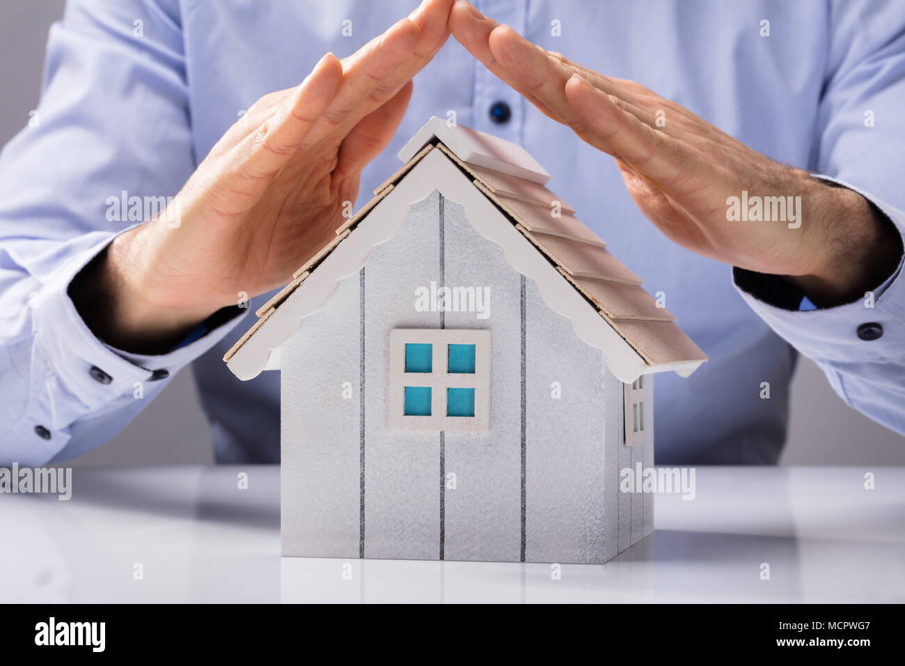 Close-up di una mano umana proteggere il modello della Casa Bianca sulla scrivania Foto Stock