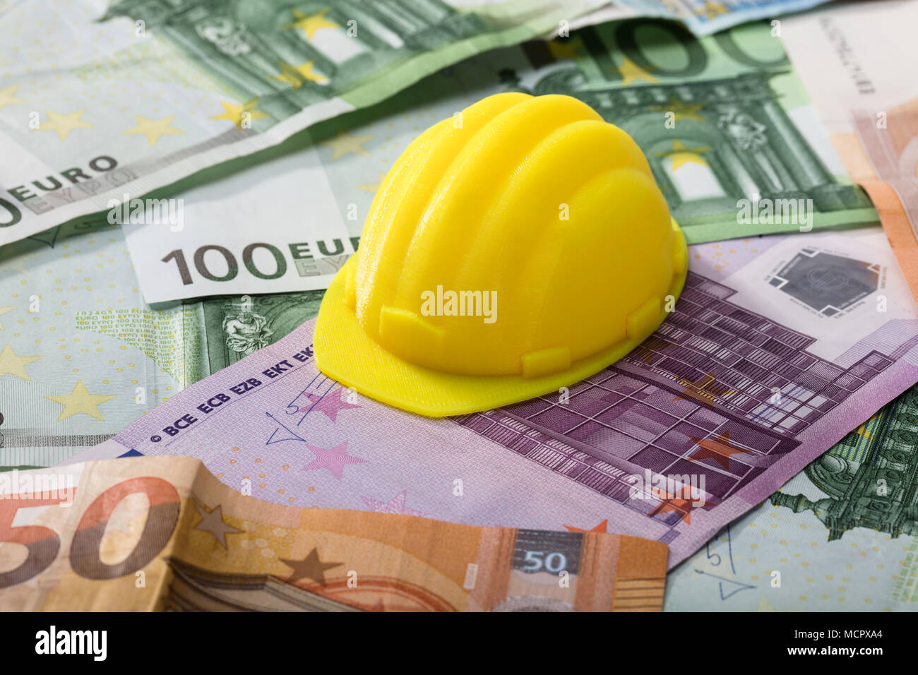 Close-up di Casco giallo sulle banconote in euro Foto Stock