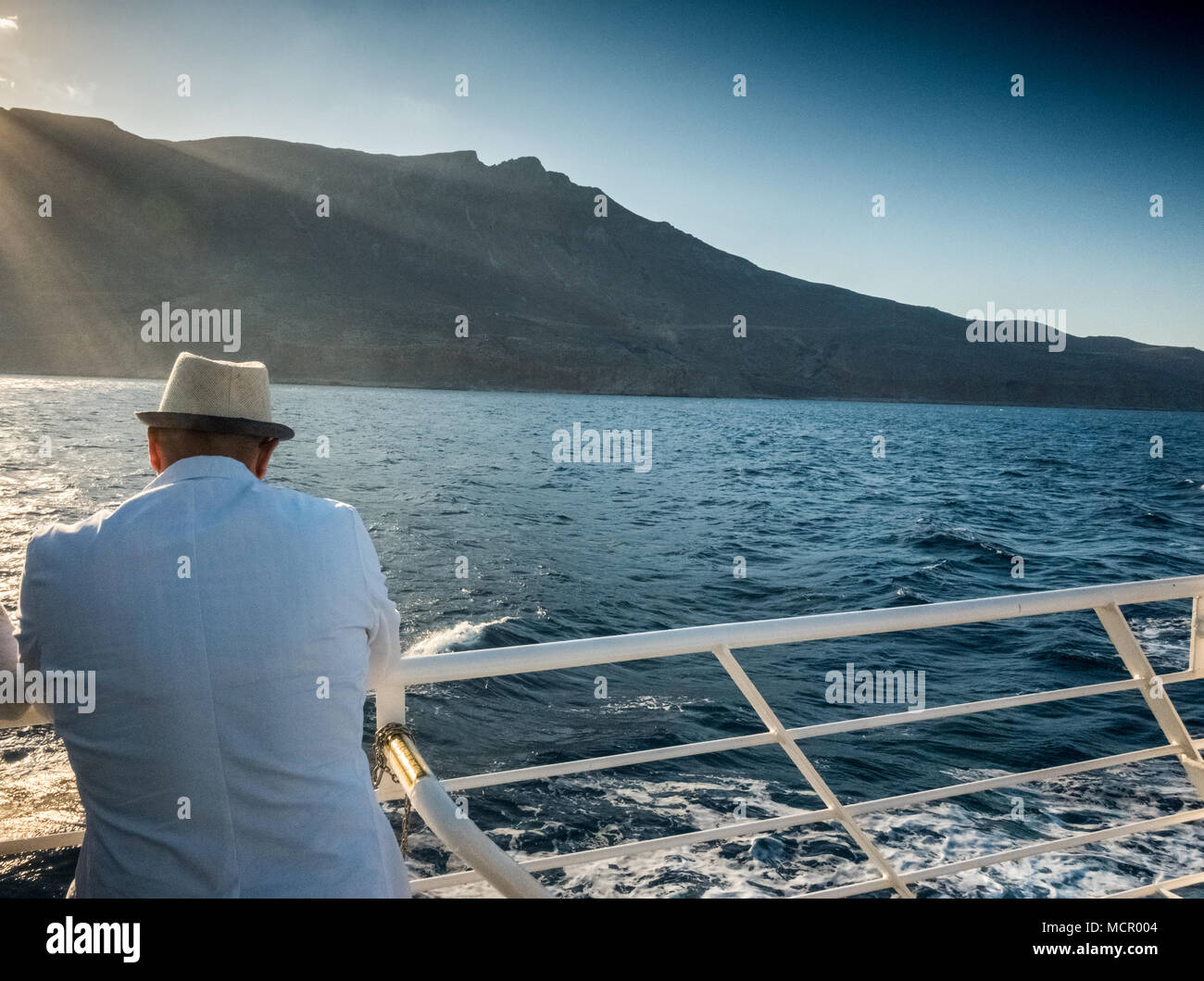 L'uomo ammirando vista panoramica del mare e montagna da barca, Creta, Grecia Foto Stock