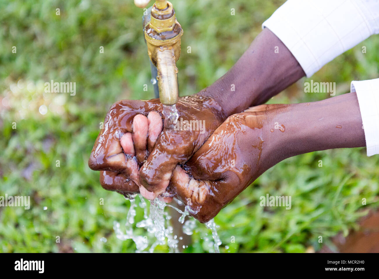 Bambini ugandesi lavare le mani in un esterno di rubinetto di acqua Foto Stock