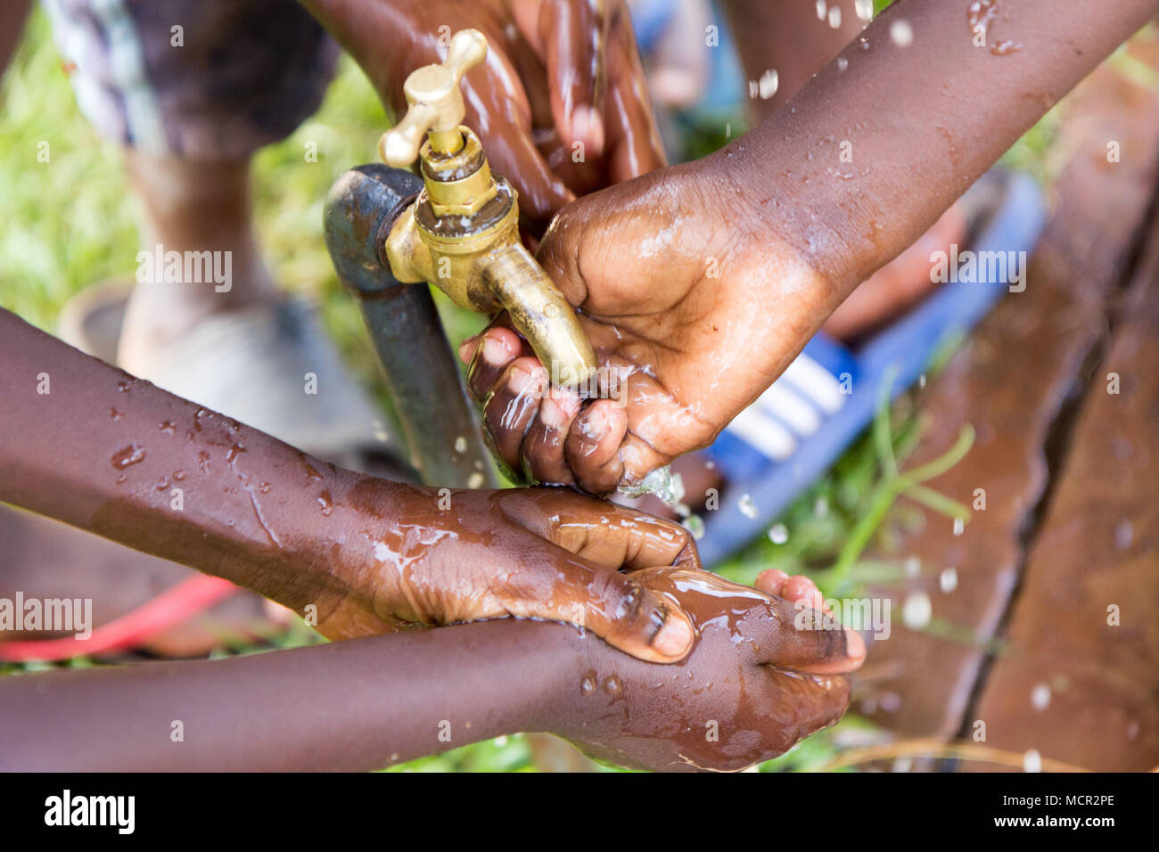 Bambini ugandesi lavare le mani in un esterno di rubinetto di acqua Foto Stock