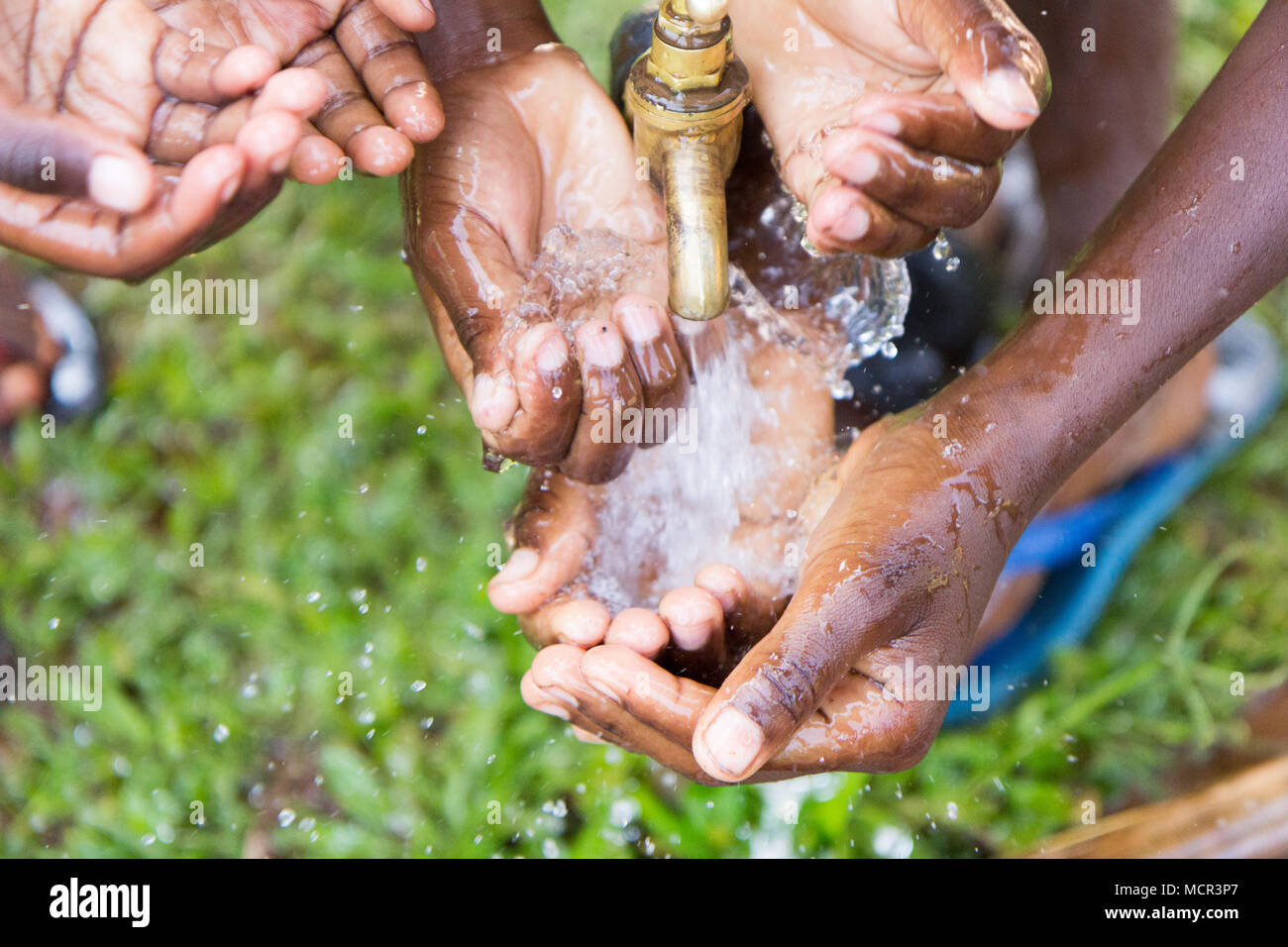 Bambini ugandesi lavare le mani in un esterno di rubinetto di acqua Foto Stock