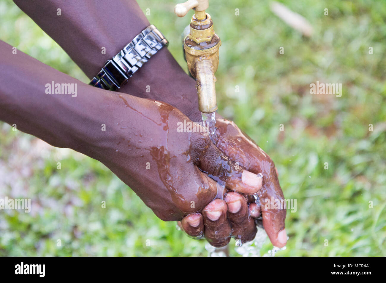 Bambini ugandesi lavare le mani in un esterno di rubinetto di acqua Foto Stock