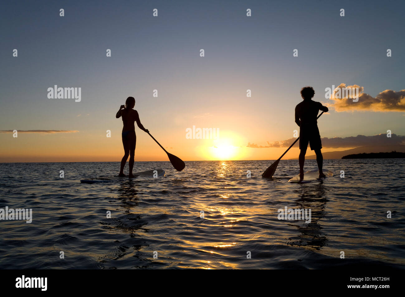 Giovane standup paddling al tramonto a Olowalu, Maui, Hawaii. Foto Stock