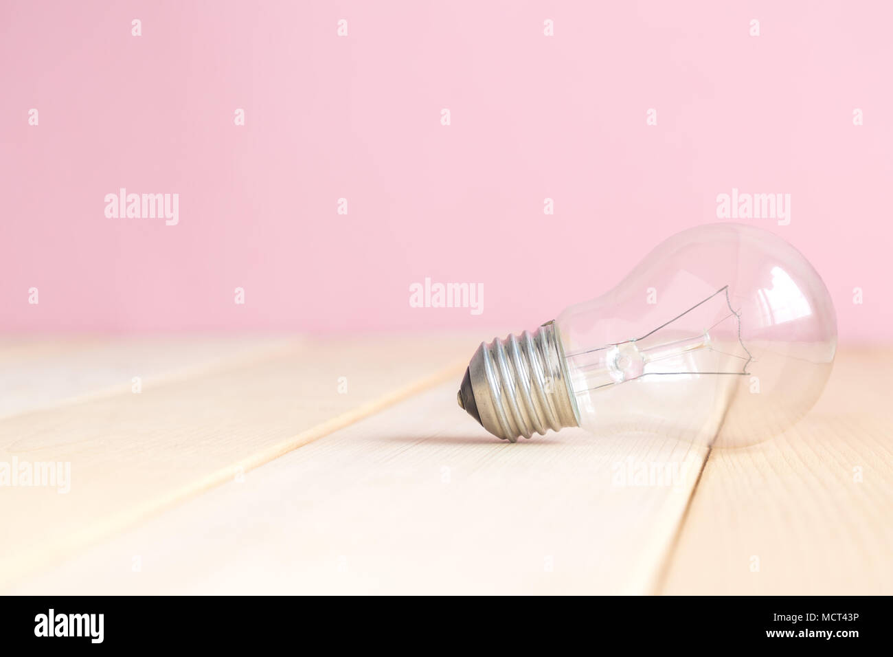 Close up della lampadina della luce sulla scrivania contro di rosa pastello minima di sfondo concetto creativo. Foto Stock