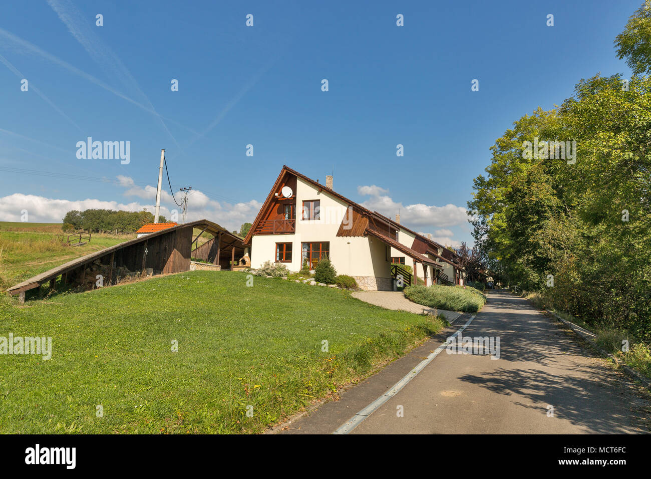 Strada rurale con tipici cottages in una riga, blu cielo chiaro e colline in background Foto Stock