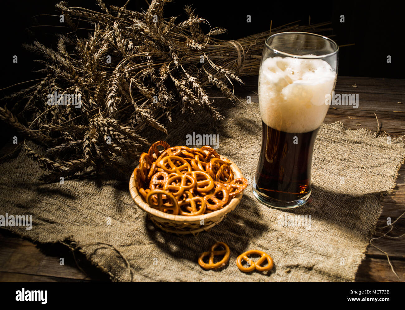 Vetro con birra di frumento e cesto di salatini Foto Stock