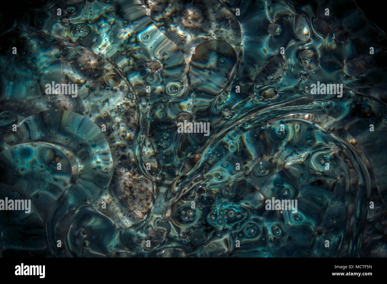 Flottante di turbolenza di olio sulla superficie dell'acqua quando l'acqua che scorre lentamente Foto Stock