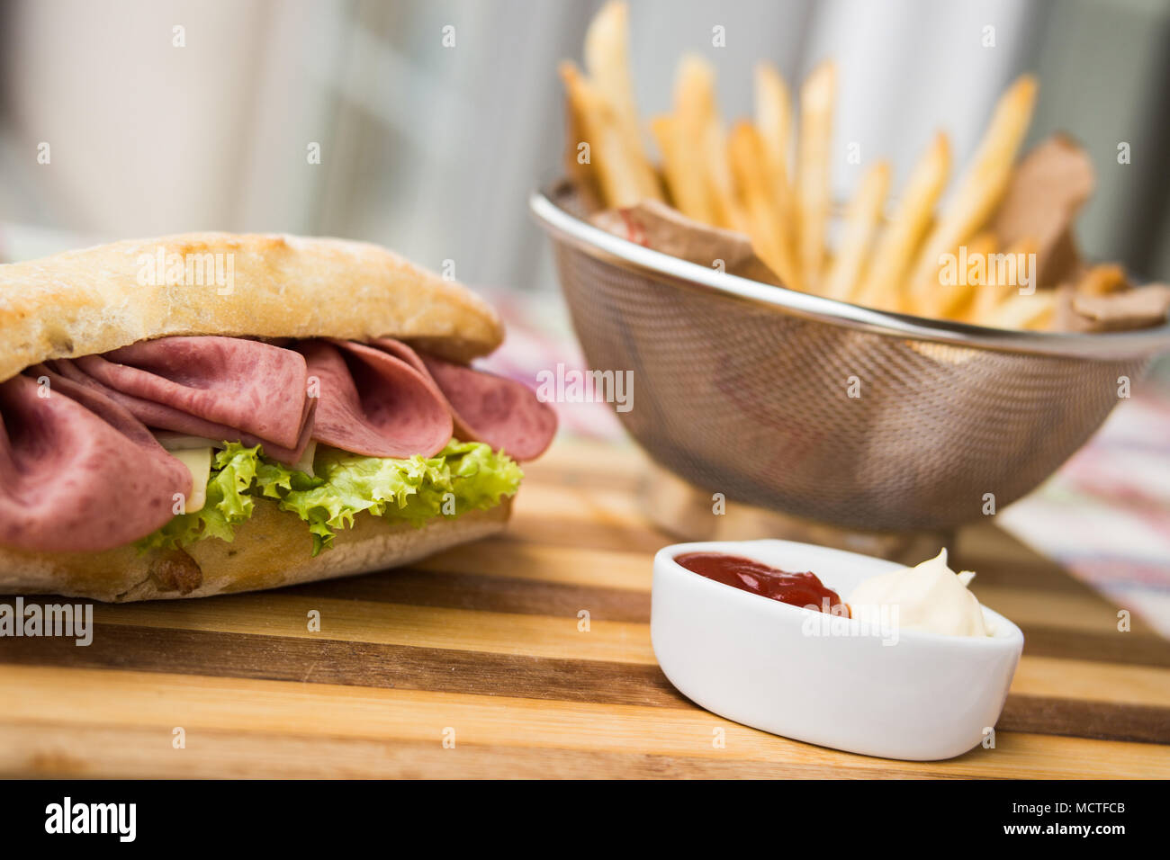 In casa panino di prosciutto con patate fritte (patatine fritte), ketchup e maionese Foto Stock