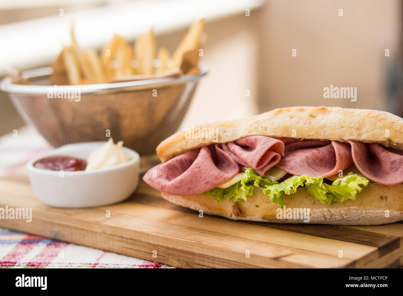 In casa panino di prosciutto con patate fritte (patatine fritte), ketchup e maionese Foto Stock
