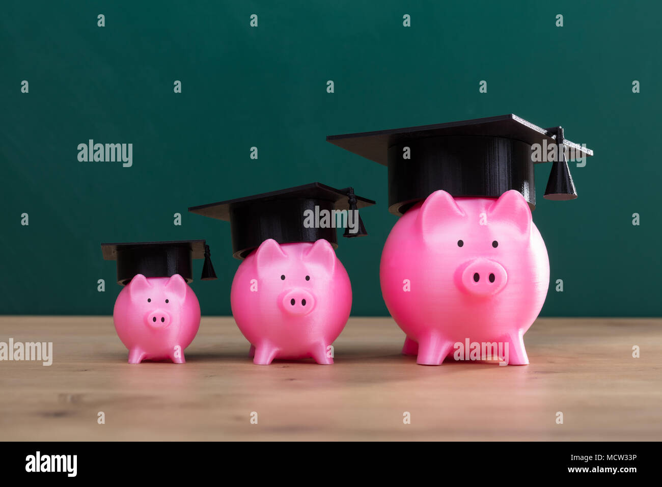 Aumentare Rosa Piggy banche con graduazione Hat disposti in una fila Foto Stock