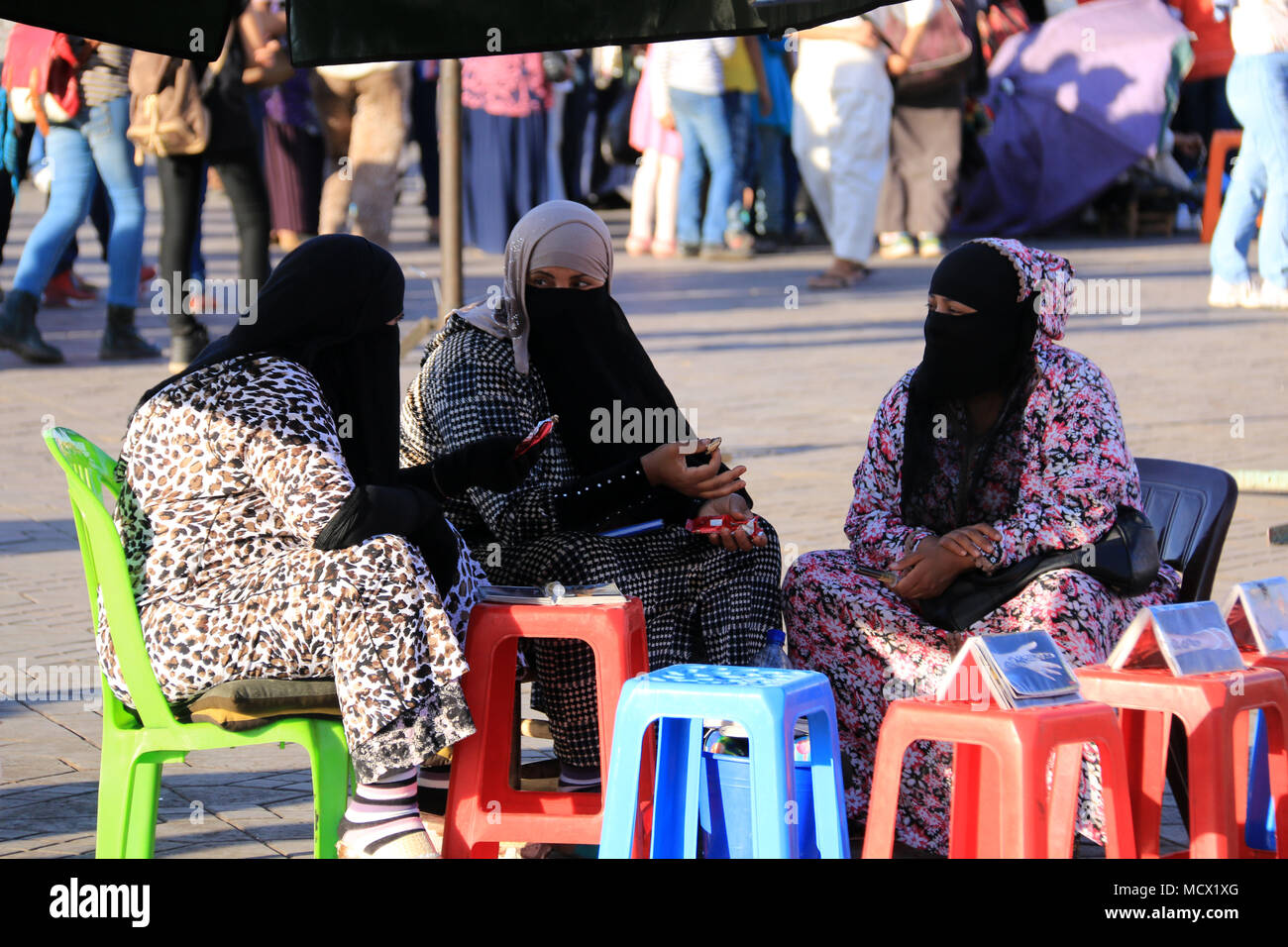Coperto le donne musulmane che danno tradizionale Henna Tattoos in attesa per i clienti presso la famosa Piazza Jemaa El Fnaa di Marrakech, Marocco Foto Stock